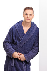 Wall Mural - Young man in a blue bathrobe leaning against a wall