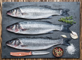 Wall Mural - Seabass on a graphite board with spices and herbs.