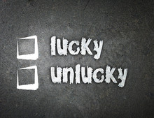 Lucky And Unlucky Handwritten With White Chalk On A Blackboard.