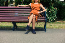 Young Woman Sitting On Park Bench