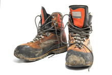 A Pair Worn Hiking Boots Isolated On A White Background.