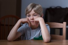Dissatisfied Kid Sitting At Table