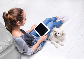 Young woman sitting on floor and using tablet .