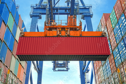 Fotografía Shore crane loading containers in freight ship