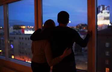 Couple embracing and looking at evening city together