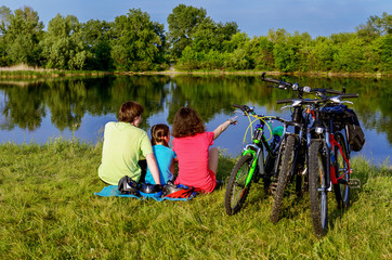 Wall Mural - Family bike ride outdoors, active parents and kid cycling and relaxing near beautiful river
