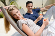 © W PRODUCTION - beautiful young couple having drink in deck chairs by the pool in holiday resort