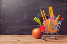 Shopping Cart With School Supplies Over Chalkboard Background