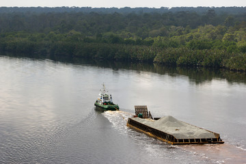 A tug boat pulling a pontoon on the river Sunga Belait, Brunei