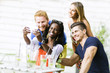 © NDABCREATIVITY - A group of friends sitting a table and talking smiling  while ta