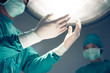 hands in surgical gloves on operation room on background of surgical lamp