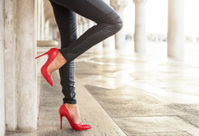 Standing Woman In Black Leather Pants And Red High Heel Shoes