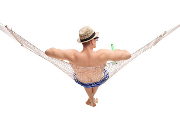 Young man lying in a hammock and holding a beer