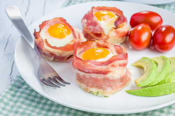 Baked eggs with avocado in bacon cups for breakfast