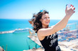 © aboutmomentsimages - I love selfie! portrait of beautiful brunette girl taking photographs of herself, selfies, on the shore at seaside. modern concept of social life, instagram