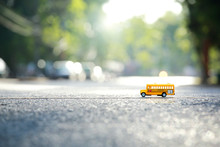 Yellow School Bus Toy Model The Road Crossing.Shallow Depth Of Field Composition And Afternoon Scene.