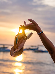 Wall Mural - Woman on the beach in Bali Indonesia holding her sandals sunset