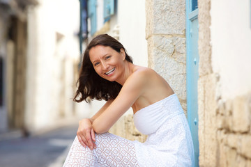 Happy woman sitting outside in summer dress