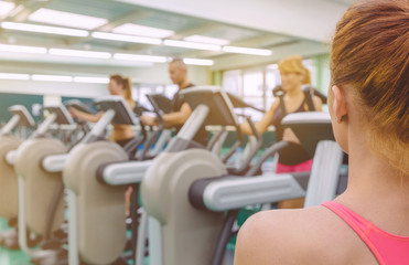 Wall Mural - Woman coach looking people in elliptical trainer session