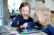 © MNStudio - Two little sisters playing with a digital tablet