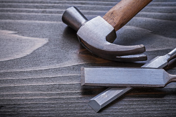 Claw hammer and flat chisels on vintage wood board construction