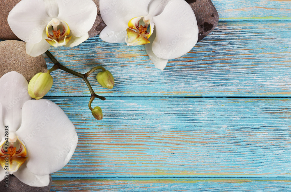 Spa stones and orchid flower on wooden background
