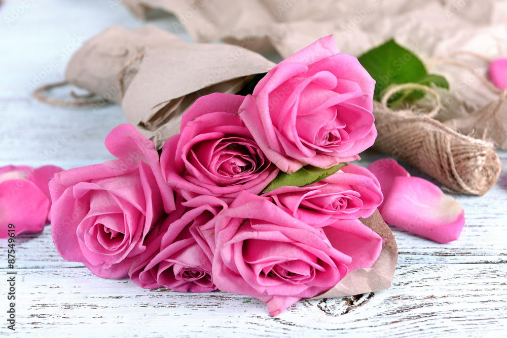 Beautiful pink roses on wooden table with parchment, closeup