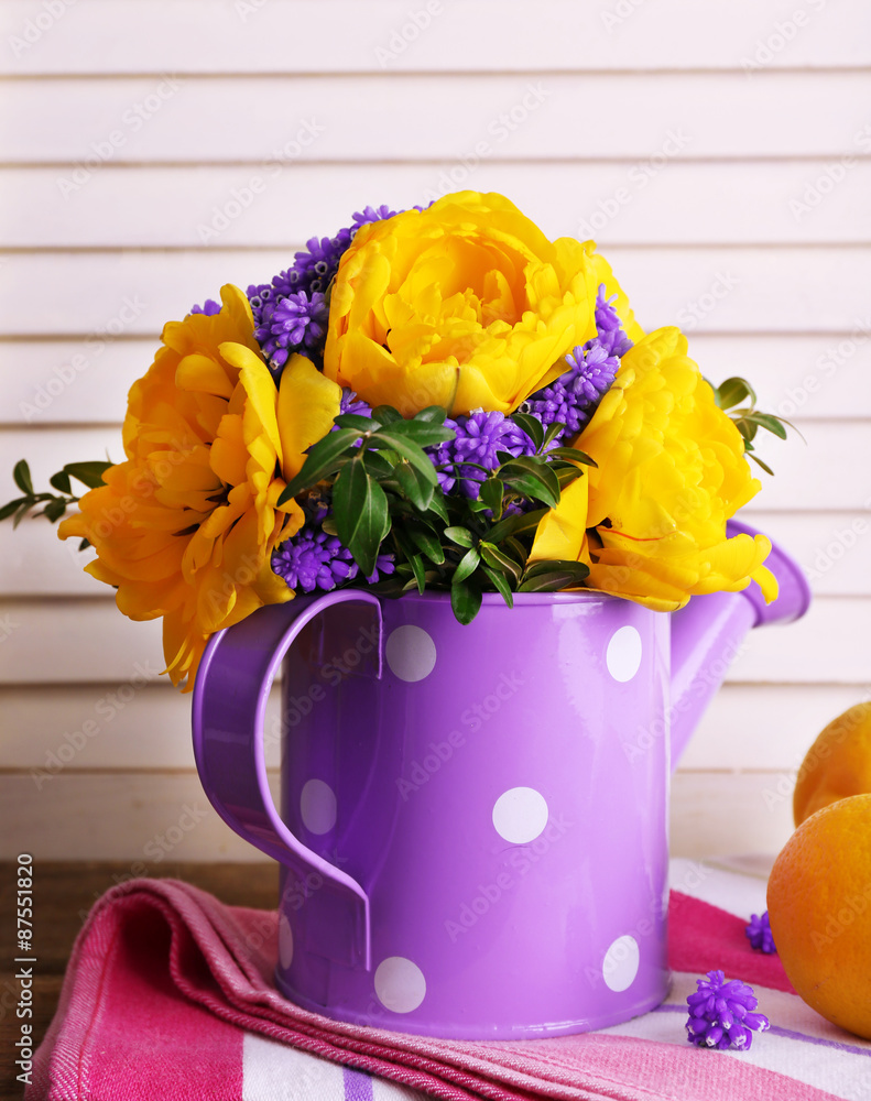 Composition with fresh spring flowers in water can on wooden background