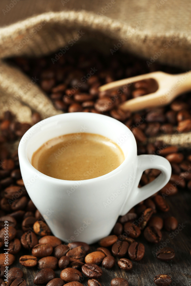 Cup of coffee with beans on table close up