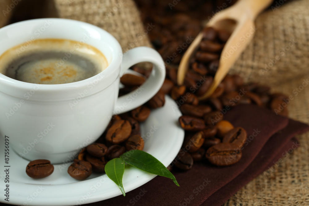 Cup of coffee with beans on table close up