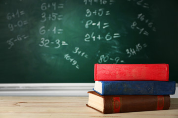 Poster - Stack of books on desk, on blackboard background