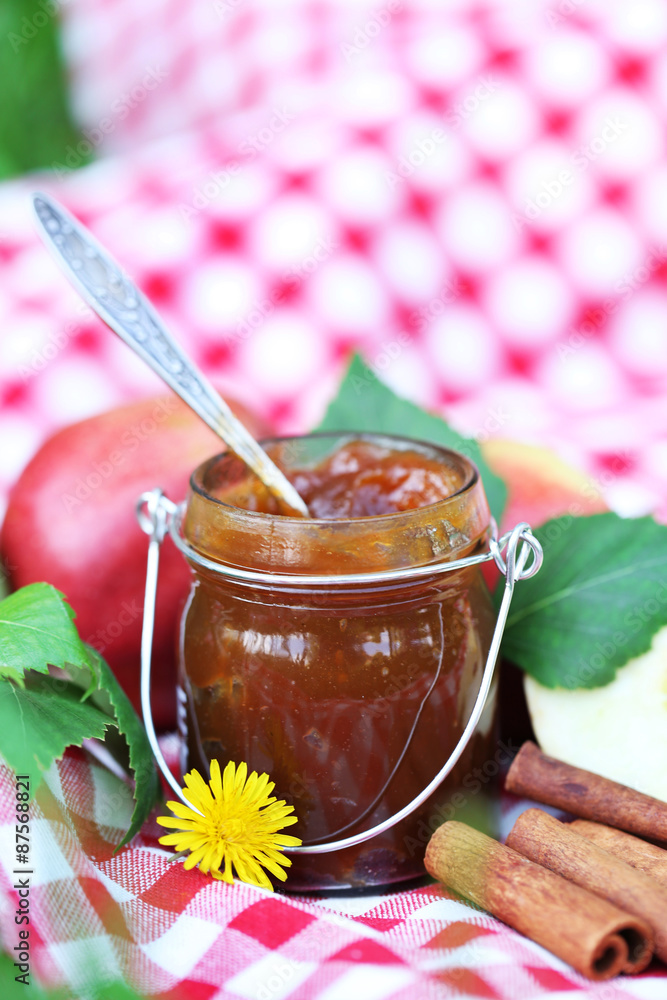 Apple jam in jar and fresh red apples outdoors