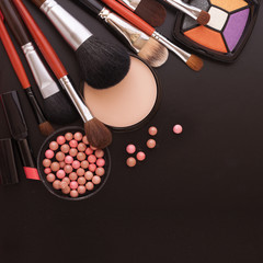 Various makeup products on dark black background with copyspace