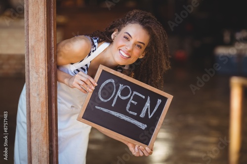 Fotografie, Obraz Hiding waitress showing chalkboard with open sign