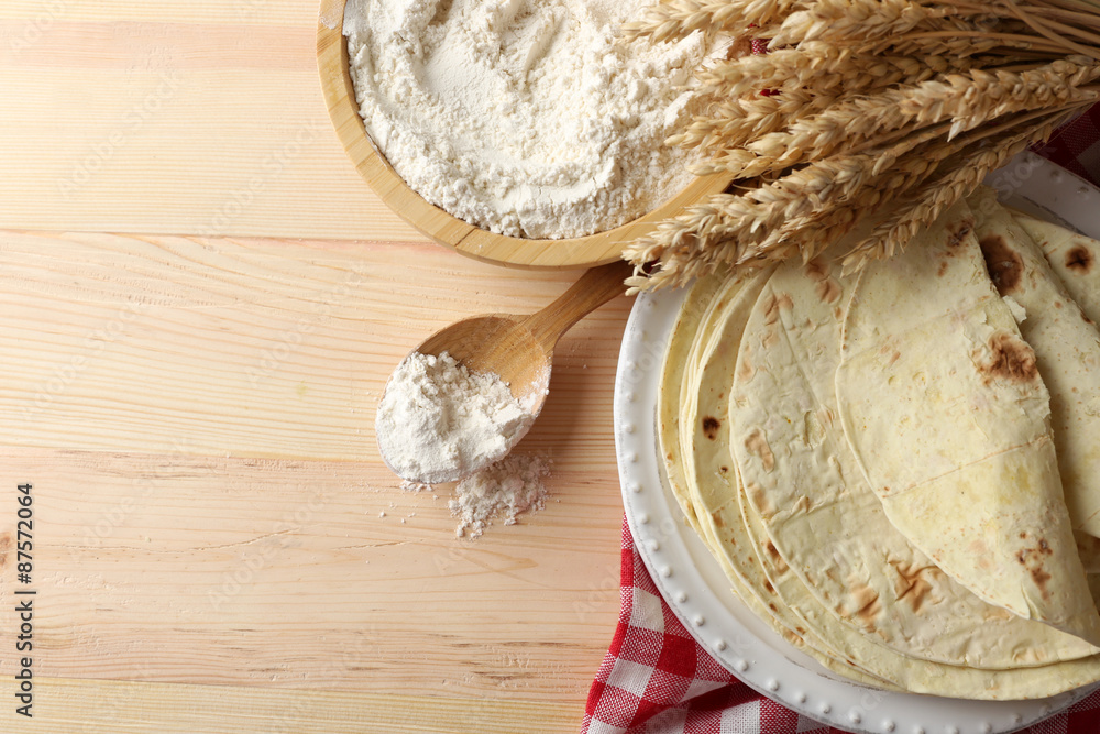 Stack of homemade tortilla on plate, on wooden table background