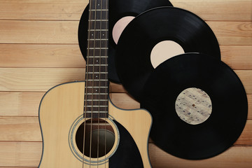 Guitar and vinyl records on wooden table close up