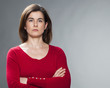 serious young woman with brown hair and red sweater staring with arms crossed for reinsurance and protection