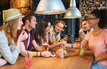 Canvas Print - happy friends with drinks talking at bar or pub