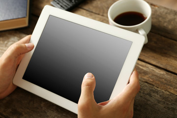 Hands holding digital tablet on wooden table background