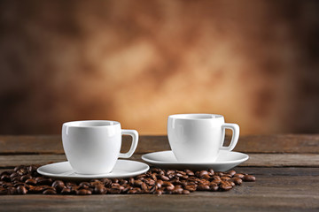 Cups of coffee and beans on blurred background