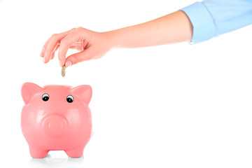 Hand inserting money into piggy bank isolated on white