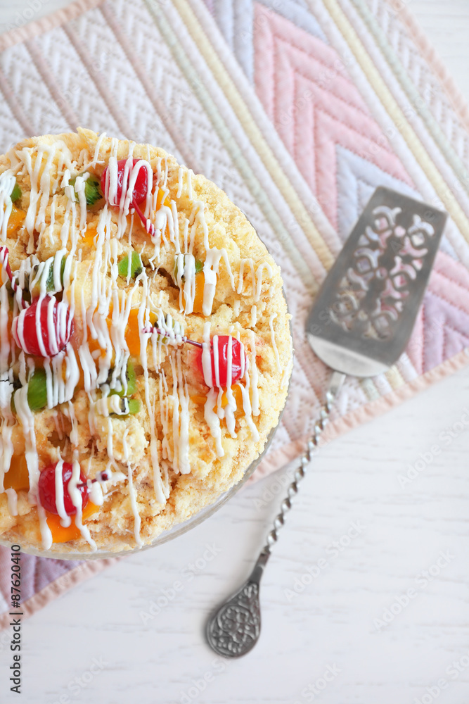 Butter cake with cherries on stand, on color wooden background