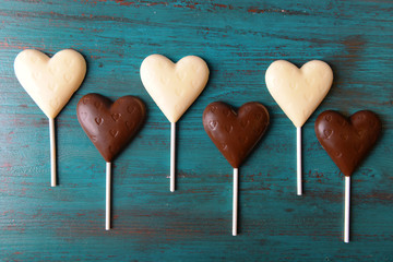 Poster - Chocolate heart shaped candies on sticks on wooden background