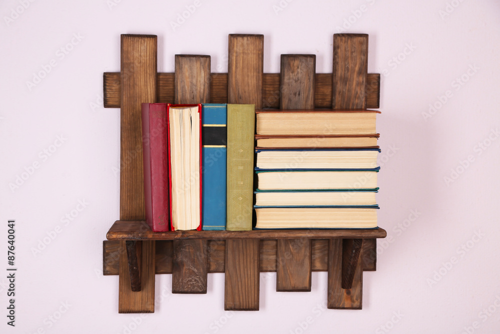 Wooden shelf with books on wall background