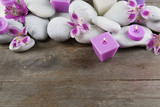 Fototapeta Kwiaty - Spa still life with purple flowers, pebbles and candlelight on wooden background
