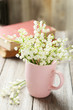 Lily of the Valley in cup on grey wooden background