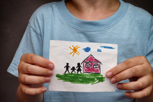 Child Holds A Drawn House With Family