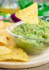 Wall Mural - Bowl with chunky guacamole served with nachos and ingredients on backgroung