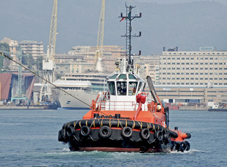 Wall Mural - A tugboat pushes the cargo ship outside the port area. 