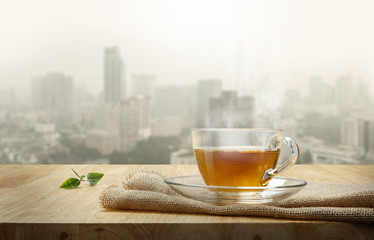 Wall Mural - Cup of tea with sacking on the wooden table and the city backgro